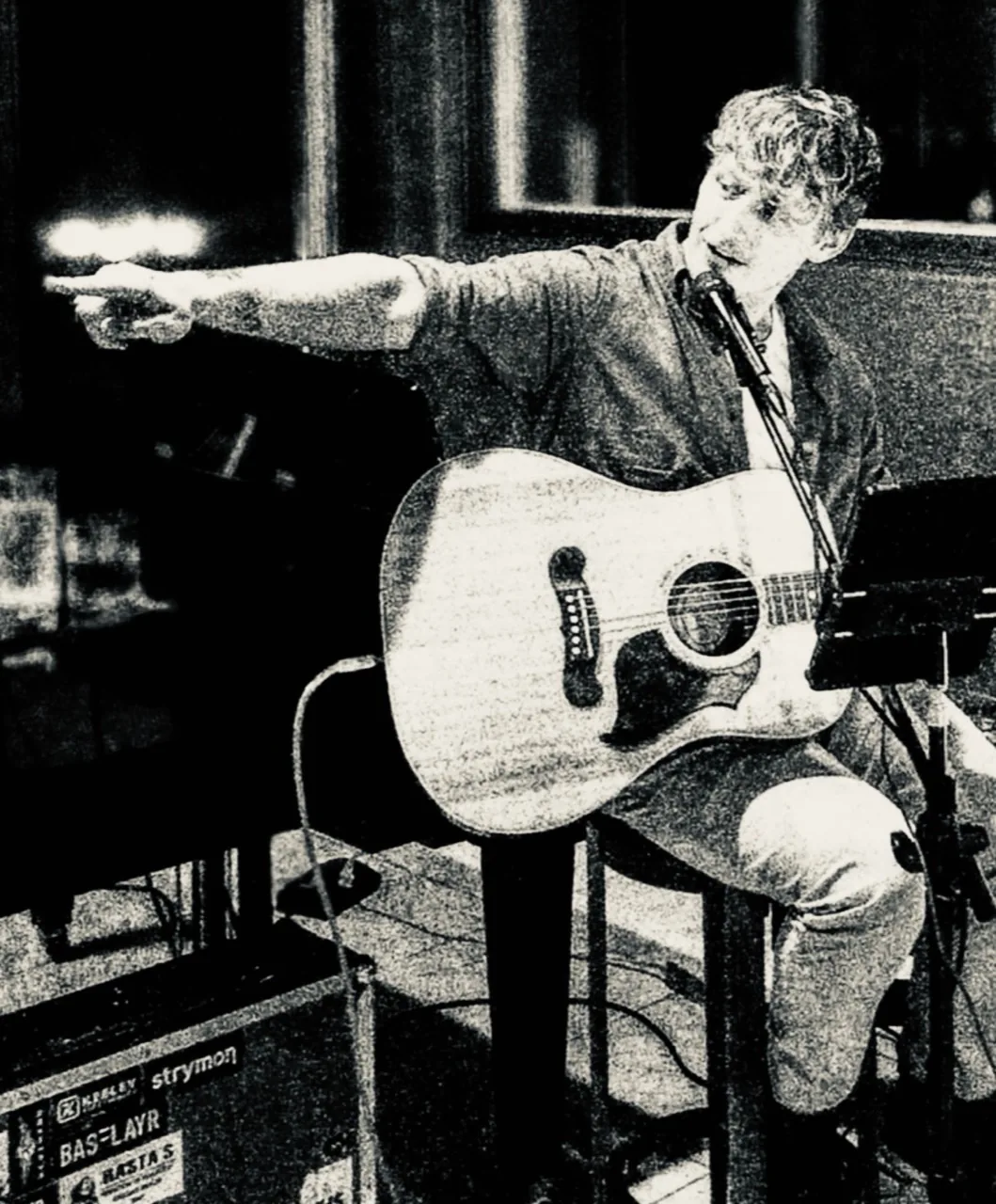 Black-and-white performance image of Easton Thomas singing and playing acoustic guitar